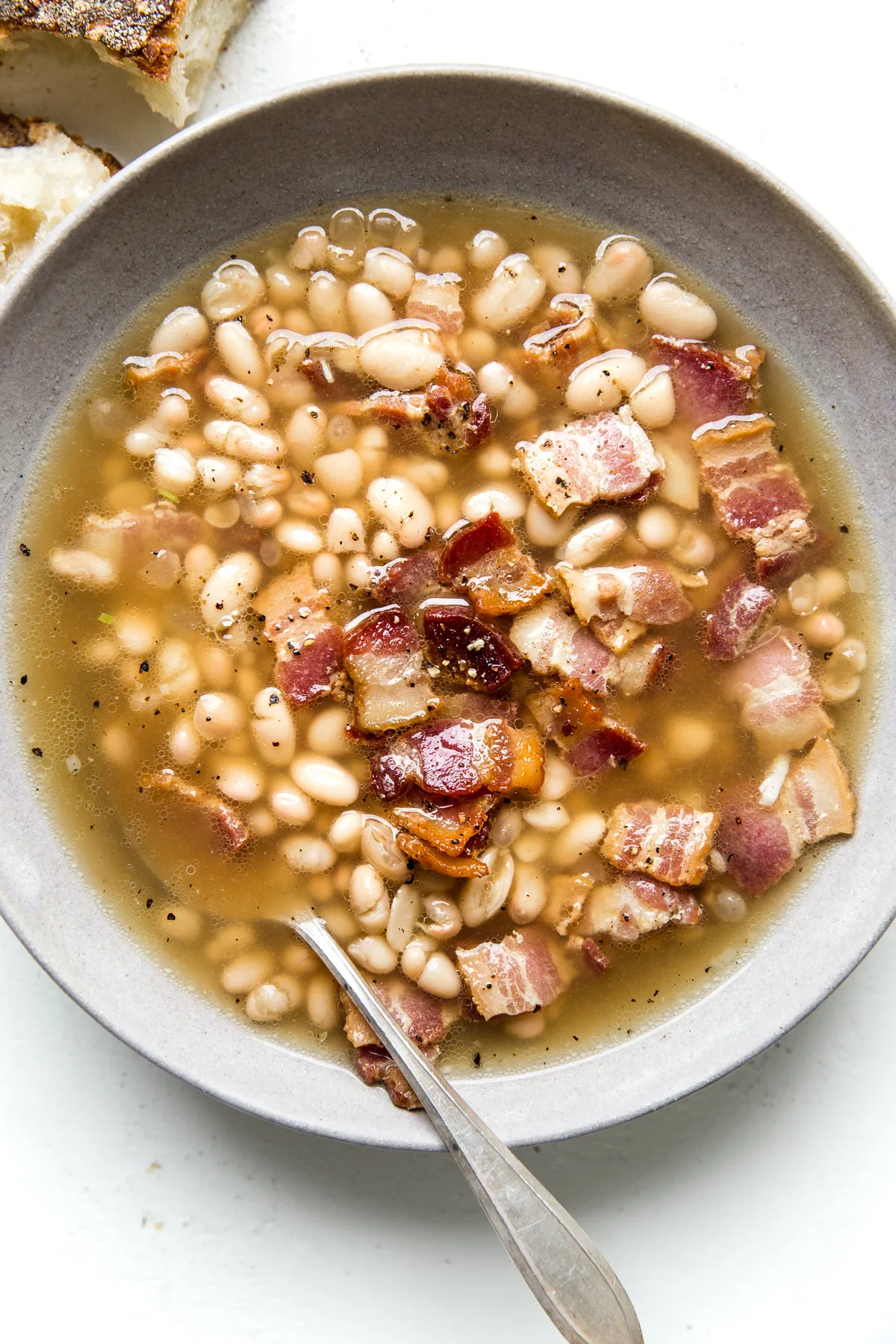 white bean and bacon soup in a bowl with a spoon