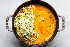 Coconut curry doodle ramen with mushrooms and red bell peppers in a soup pot zucchini noodles Vegan curry vegetarian curry.