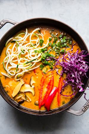 Coconut curry ramen with zucchini noodles, mushrooms in a bowl with chop sticks. Vegan curry vegetarian curry in a pot.
