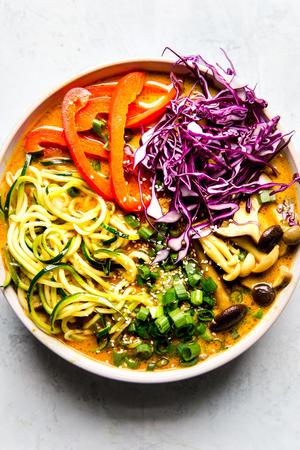 Coconut curry zoodle ramen with zucchini noodles, mushrooms in a bowl with chop sticks. Vegan curry vegetarian curry.