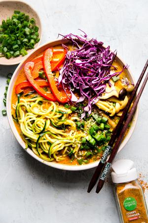 Coconut curry zoodle ramen with zucchini noodles, mushrooms in a bowl with chop sticks. Vegan curry vegetarian curry.