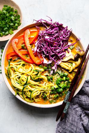 Coconut curry zoodle ramen with zucchini noodles, mushrooms in a bowl with chop sticks. Vegan curry vegetarian curry.