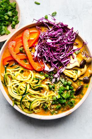 Coconut curry zoodle ramen with zucchini noodles, mushrooms in a bowl with chop sticks. Vegan curry vegetarian curry.