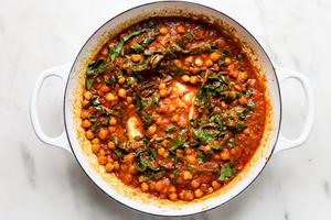 chickpeas with tomato sauce and swiss chard shown in a large white skillet
