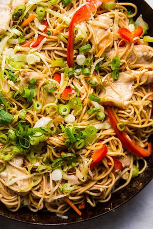 homemade chicken chow mein with bell peppers, celery, carrots and a sauce in a skillet