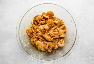 raw chicken breast pieces velveted in a bowl with cornstarch and soy sauce