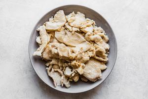 chicken pieces in a bowl that has been tossed in salt, soy sauce and cornstarch and then poached