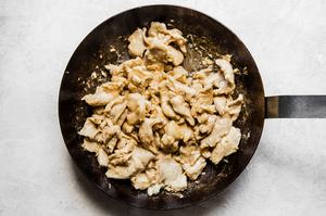 poached chicken pieces and garlic cooking in a large skillet