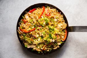 homemade chicken chow mein with bell peppers, celery, carrots and a sauce in a skillet