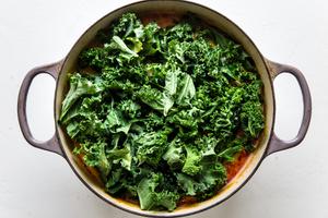large pot of coconut curry soup topped with raw kale