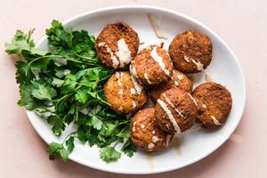 a platter of homemade falafel drizzled with tahini sauce and served with parsley