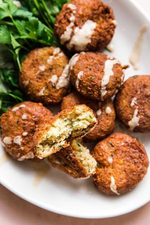 falafel on a white plate drizzled with tahini sauce