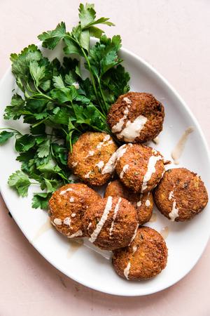 a platter of homemade falafel drizzled with tahini sauce and served with parsley