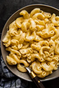 Instant pot mac and cheese in a bowl sprinkled with pepper with a spoon and linen.
