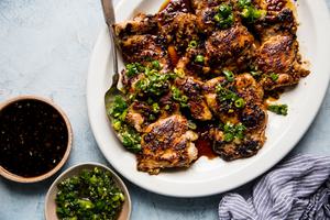 lemongrass chicken thighs with scallion oil and a sriracha-brown sugar sauce on a plate with a spoon