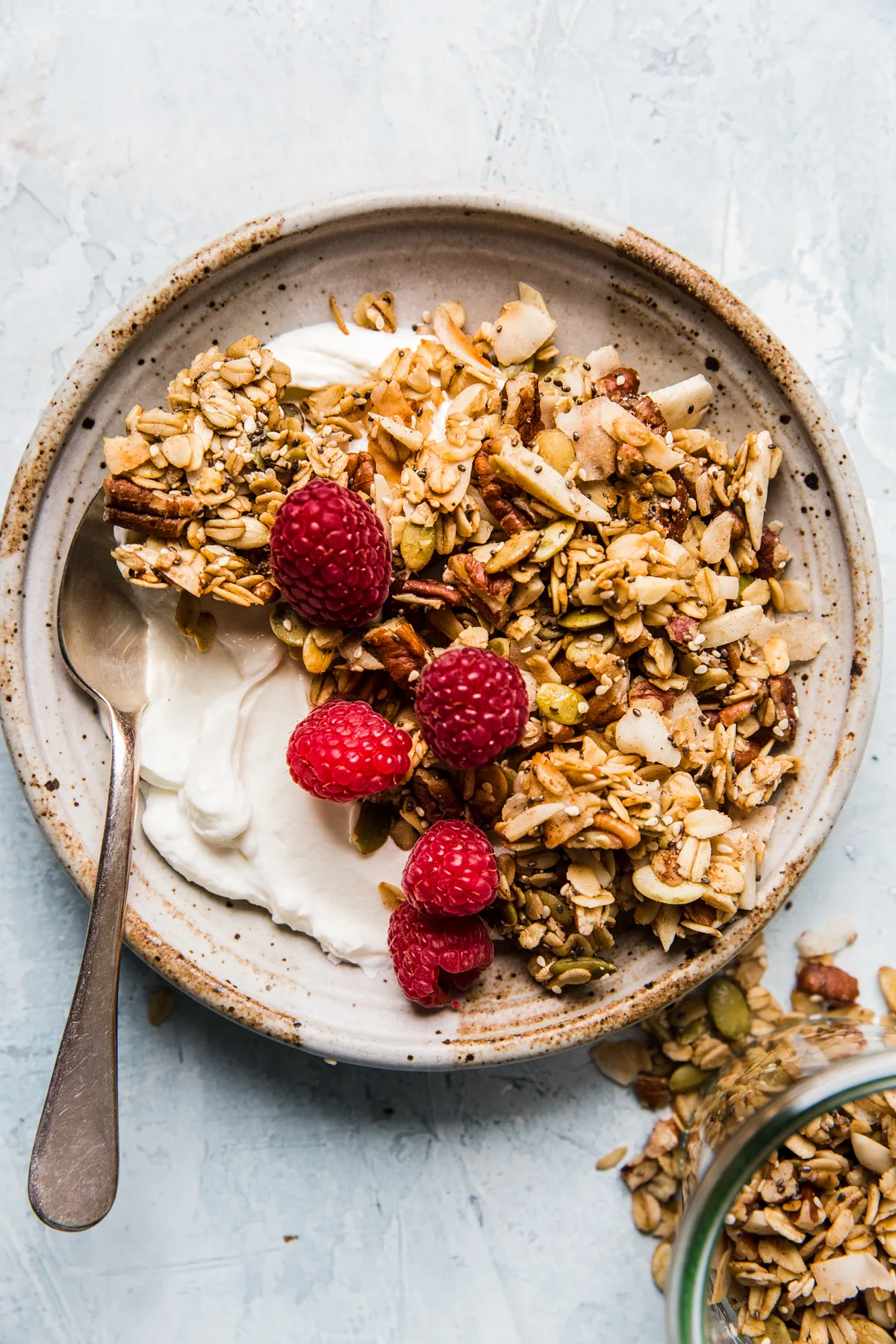 nuts and seeds granola with oats, yogurt and fresh raspberries in a bowl in a list of easy granola breakfast recipes