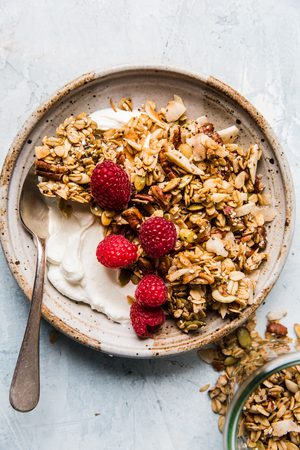 nuts and seeds granola with oats, yogurt and fresh raspberries in a bowl in a list of easy granola breakfast recipes