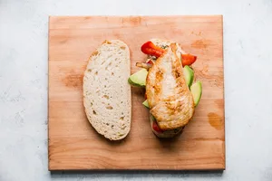 two slices of sourdough bread with grilled chicken, peppers, onions and her mayo on one half.