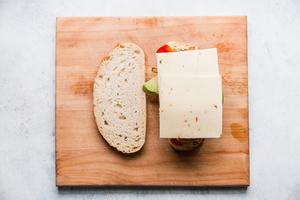 two slices sour dough bread with peppers, onions, mayo, avocado, grilled chicken and pepper jack cheese on one half.