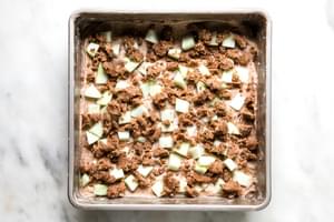 homemade apple crumb cake batter topped with apples and crumb topping in a baking pan ready for the oven