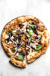 BBQ. chicken pizza shown with a slice out of it.