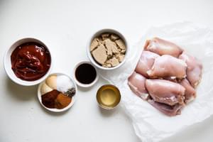 ketchup, spices, brown sugar apple cider vinegar and Worcestershire sauce for homemade bbq sauce, next to raw chicken thighs