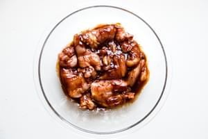 raw boneless skinless chicken thighs in a bowl with homemade bbq sauce
