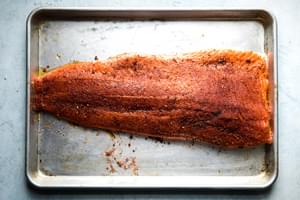 raw salmon fillet on a baking sheet seasoned with brown sugar, salt, paprika, garlic powder and pepper