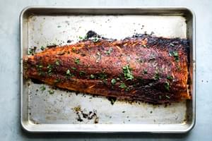 1 baked salmon fillet on a baking sheet seasoned with brown sugar, salt, paprika, garlic powder and pepper
