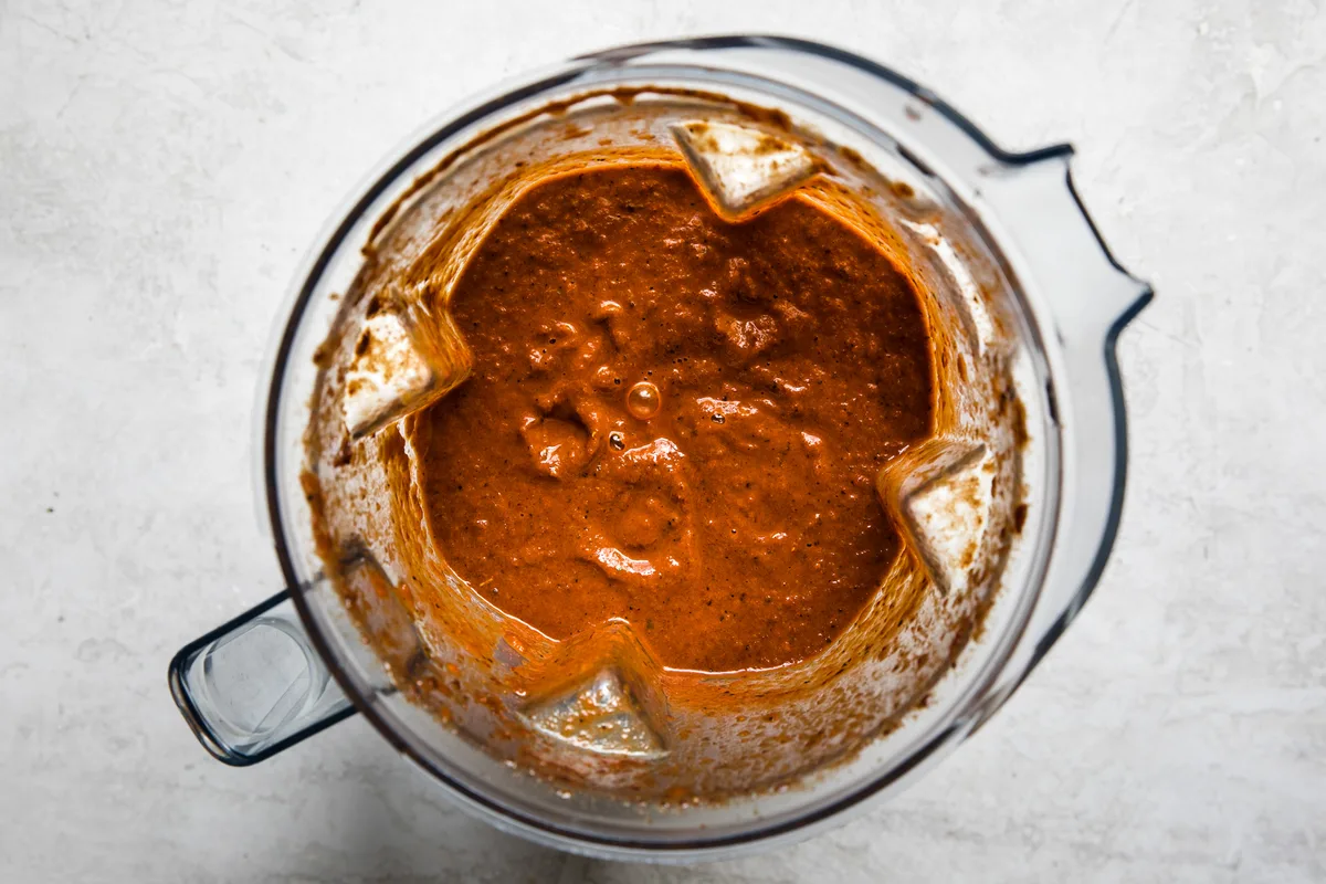 a blender full of smooth, rich, velvety birria sauce ready to go on beef