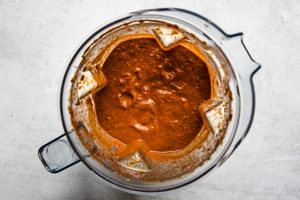 a blender full of smooth, rich, velvety birria sauce ready to go on beef