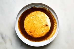 corn tortillas being dipped in beef birria consommé sauce