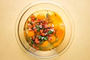 raw eggs and pico de Gallo in a mixing bowl on the counter