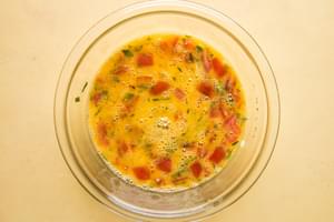 raw eggs and pico de Gallo in a scrambled together in a mixing bowl on the counter