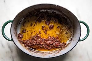 garlic, whole grain mustard and tomato paste being cooked in a dutch oven for braised brisket