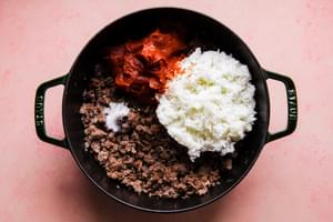 ground beef and pork sausage browned with onion, white rice, tomato paste and ketchup in a Dutch oven