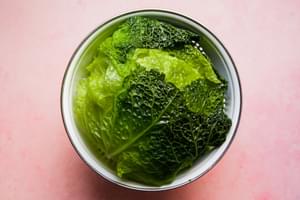 a head of boiled cabbage leaves in a strainer to prepare polish cabbage rolls
