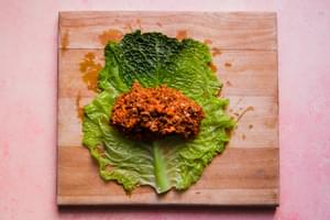 a boiled cabbage leaf being filled with a ground beef, sausage and rice mixture