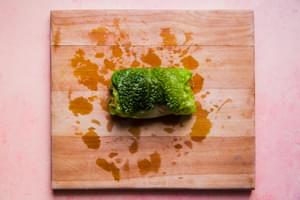 a boiled cabbage leaf being filled and rolled with a ground beef, sausage and rice mixture