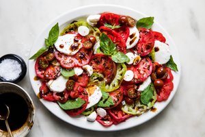 a simple caprese salad with sliced tomatoes, mozzarella and fresh basil drizzled with a homemade balsamic glaze