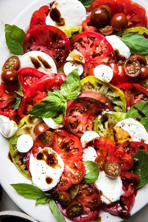 a simple caprese salad with sliced tomatoes, mozzarella and fresh basil drizzled with a homemade balsamic glaze