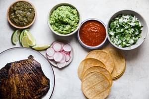 carne asada, corn tortillas, onion and cilantro, radishes, salsa, guacamole and limes
