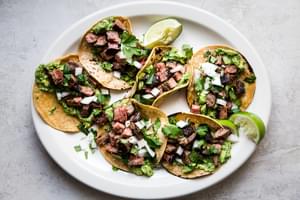 homemade carne asada tacos with onion, lime, and cilantro