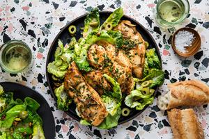 chicken paillard on a plate with a salad, served with bread and wine