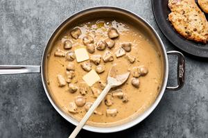 butter being stirred into marsala sauce in a skillet