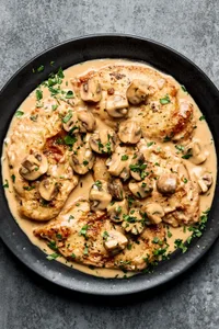 Chicken marsala on a serving platter topped with parsley. Made with mushrooms, shallots, garlic, thyme, wine and cream.