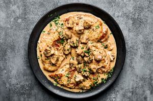 Chicken marsala on a serving platter topped with parsley. Made with mushrooms, shallots, garlic, thyme, wine and cream.