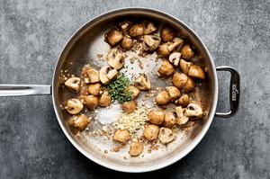 shallots, mushrooms, garlic and thyme being cooked in olive oil in a skillet