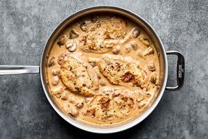 chicken being simmered in marsala wine sauce