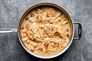 chicken being simmered in marsala wine sauce